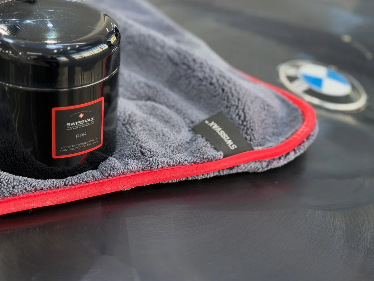 Araç yüzeyindeki Swissvax bakım ürünü ve mikrofiber bez.